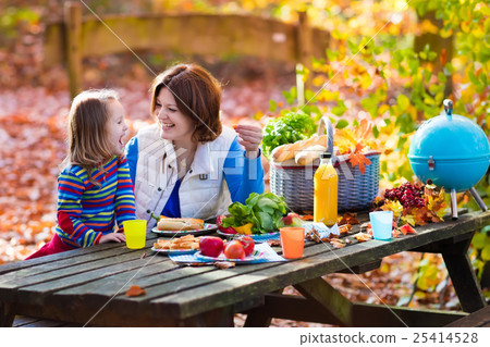 Mother and daughter set table for picnic in autumn 25414528