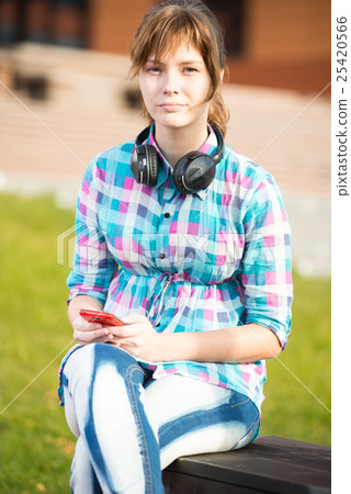 Smiling young college girl texting on a cell phone Smiling young college girl texting on a cell phone 25420566