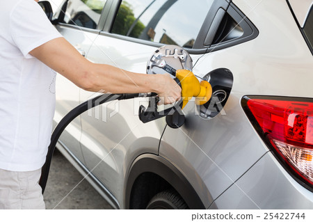 Person holding yellow nozzle fill petrol into car 25422744