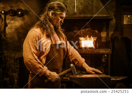 Senior blacksmith forging the molten metal on the 25425251