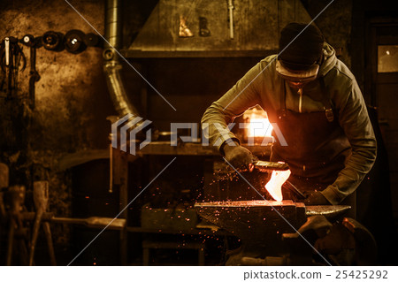 The blacksmith with brush handles the molten metal The blacksmith with brush handles the molten metal 25425292