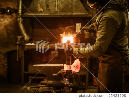 The blacksmith forging the molten metal on the 25425308