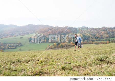 Beautiful young couple running in sunny autumn 25425568