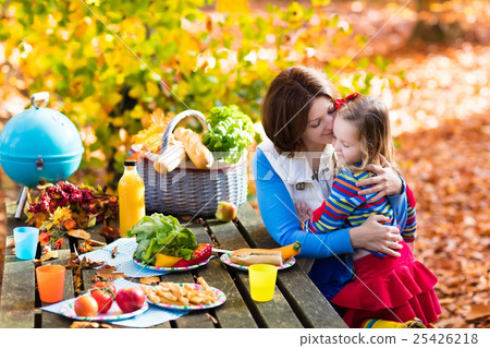 Mother and daughter set table for picnic in autumn 25426218