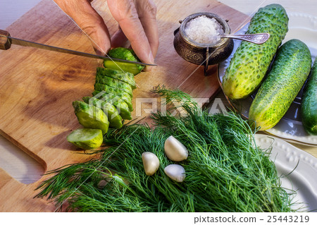 Hands slicing cucumber on the cutting board 25443219