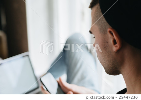 Rear view of man using cellphone and laptop Rear view of man using cellphone and laptop 25447230