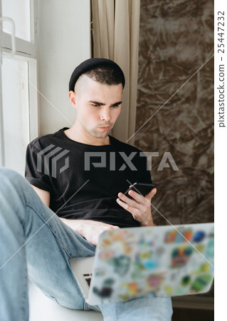 Man in black hat using laptop Man in black hat using laptop 25447232