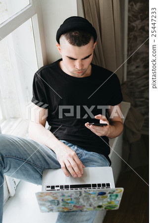 Man in black hat using laptop 25447233