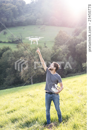 Young hipster man with flying drone. Sunny green Young hipster man with flying drone. Sunny green 25450778