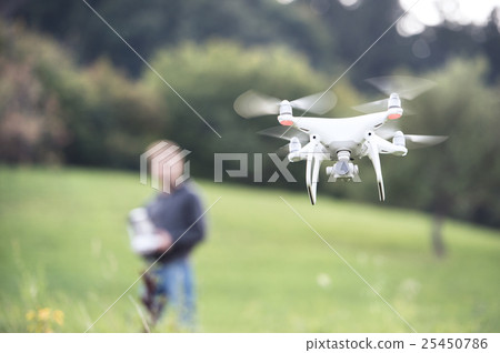 Unrecognizable man with flying drone. Sunny green 25450786