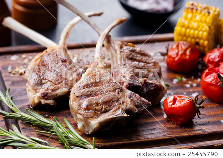 Lamb ribs grilled on cutting board with vegetables Lamb ribs grilled on cutting board with vegetables 25455790
