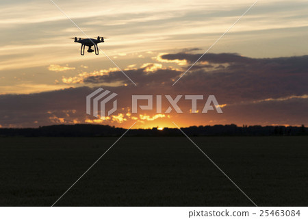 Drone silhouetted against orange sunset Drone silhouetted against orange sunset 25463084