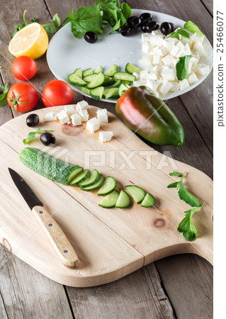 Cooking Greek salad, cutting a cucumber 25466077