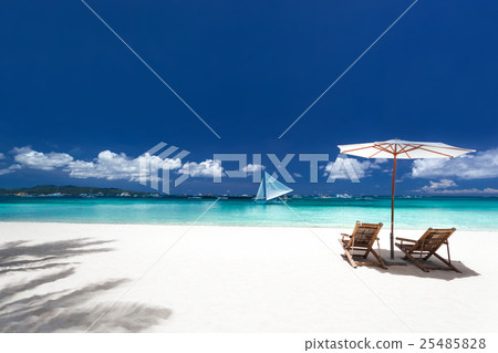 Sun umbrellas and wooden beds on tropical beach 25485828