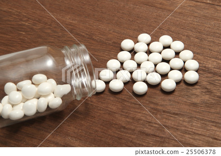 White pills spilling from a fallen transparent bottle White pills spilling from a fallen transparent bottle 25506378