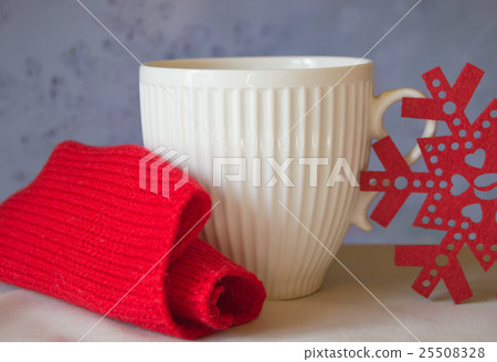 White mug and snowflake with a red knitted scarf White mug and snowflake with a red knitted scarf 25508328