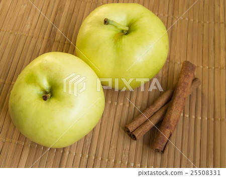 Two ripe green apples and cinnamon sticks on Two ripe green apples and cinnamon sticks on 25508331