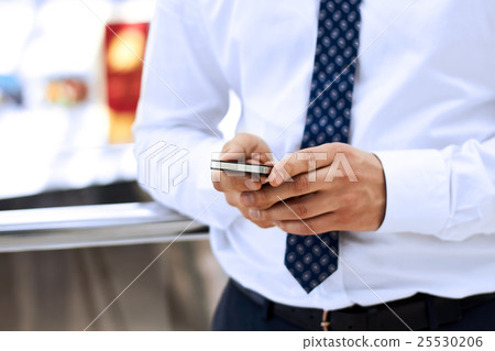 Businessman holding and using the smart phone Businessman holding and using the smart phone 25530206