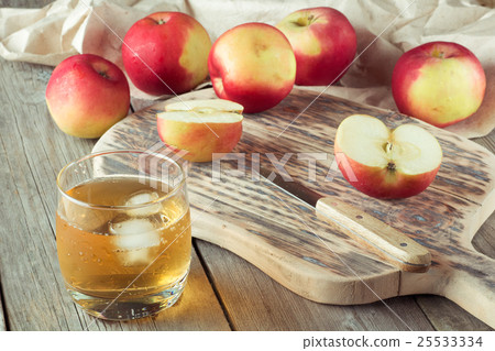 glass of juice and apples on a cutting board 25533334