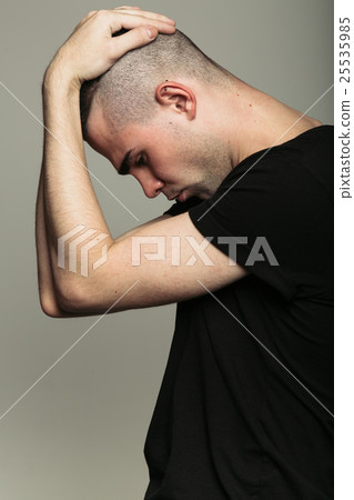 Man in black t-shirt with both hands on his head Man in black t-shirt with both hands on his head 25535985