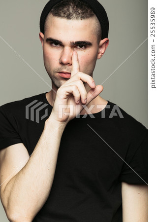 Man in black beanie putting finger to his face 25535989