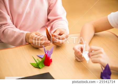 在養老院的要求室享受摺紙的老年人和年輕護理員 在養老院的要求室享受摺紙的老年人和年輕護理員 25541714