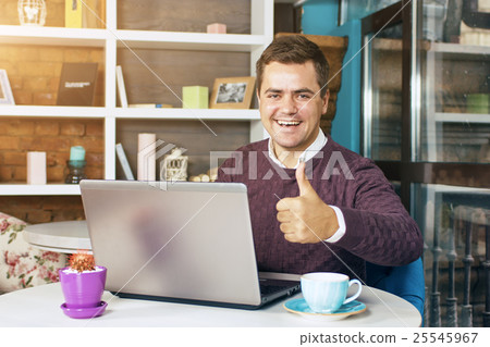 Man in a cafe with laptop smiling 25545967