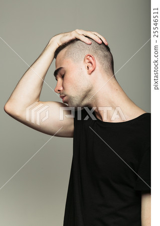 Man in black t-shirt with hand on his head 25546511