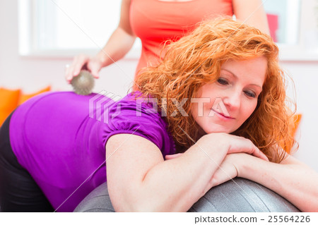 Pregnant women getting backrub with massage ball 25564226