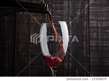Pouring red wine into the glass from bottle 25569674