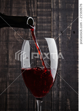 Pouring red wine into the glass from bottle 25569676