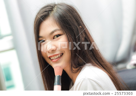 Young asian woman applying cosmetic paint brush 25573303