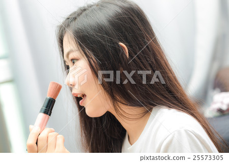 Beautiful young woman with makeup brush Beautiful young woman with makeup brush 25573305