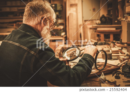 Senior restorer working with antique decor element 25592404