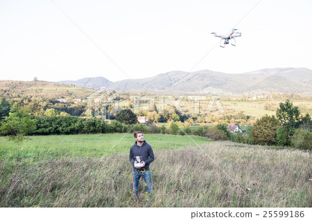 Young hipster man with flying drone. Sunny green 25599186