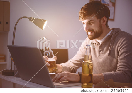 Man using laptop and having a beverage Man using laptop and having a beverage 25605921