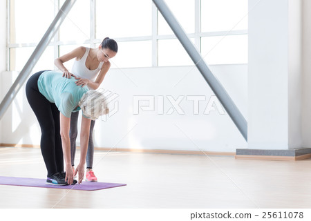 Confident fitness coach standing near the woman Confident fitness coach standing near the woman 25611078