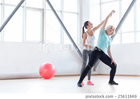 Young helpful coach standing behind a woman Young helpful coach standing behind a woman 25611669