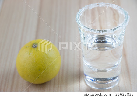 Vodka shot and salt sea, lemon  on wooden table 25623833