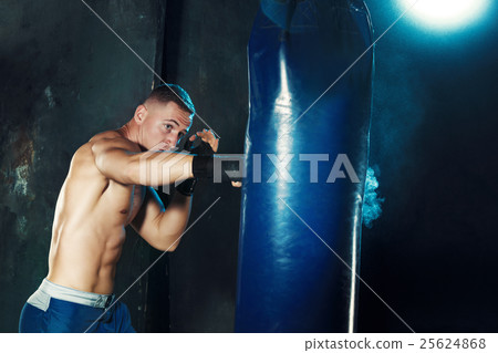 Male boxer boxing in punching bag with dramatic Male boxer boxing in punching bag with dramatic 25624868