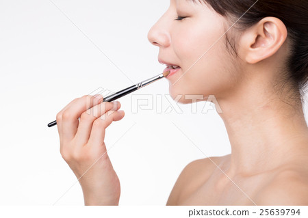 應用與刷子的一名婦女唇膏 25639794