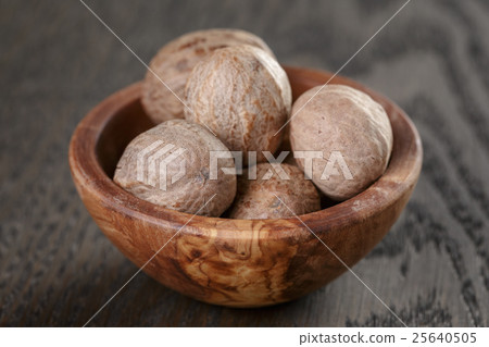 whole nutmegs in olive bowl on oak table, rustic whole nutmegs in olive bowl on oak table, rustic 25640505