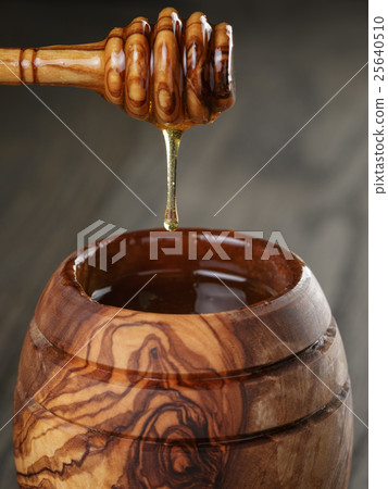 maple honey flowing from dipper to pot, rustic 25640510