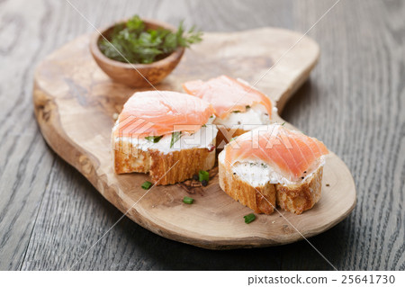baguette slices with soft cheese and salmon on wood table baguette slices with soft cheese and salmon on wood table 25641730