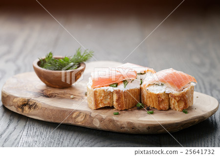 baguette slices with soft cheese and salmon on wood table 25641732