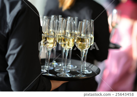 Waitress holding a dish of champagne glasses 25643458
