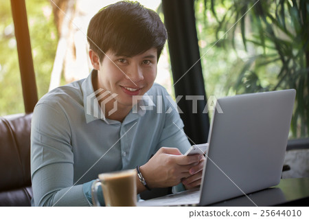 Young Asian man using laptop and smart phone 25644010