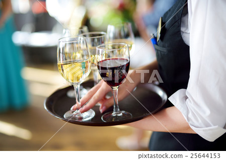 Waitress with dish of champagne and wine glasses 25644153