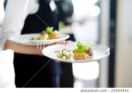 Waiter carrying plates with meat dish 25644842