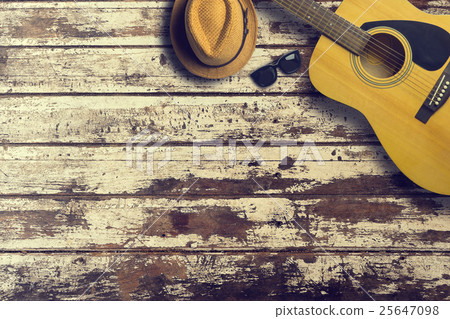 Acoustic guitar with hat and sunglasses on wooden 25647098